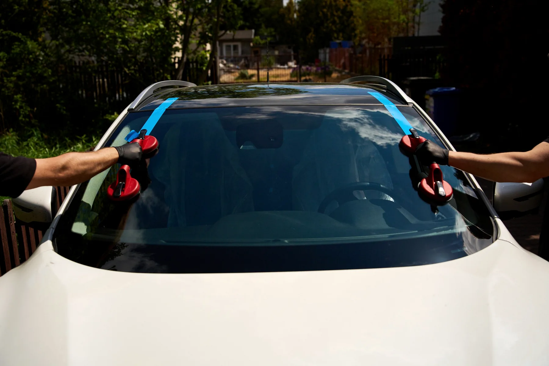 Mobile windshield technicians installing glass on a white vehicle