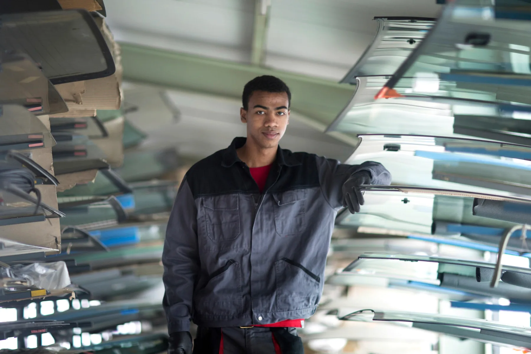 Auto glass technician standing beside windshield inventory